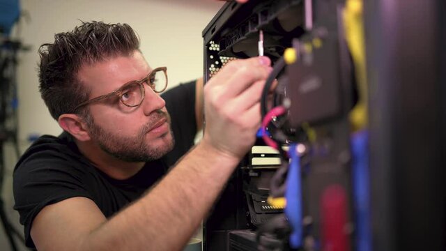 Handsome man with glasses assembling computer case concentrating on work