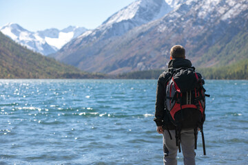 young man with a backpack looks at the river and mountains. Beautiful natural landscape