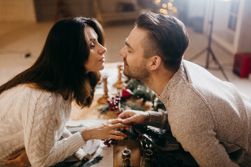 Lovely couple sit at the table with decorations, beautiful woman with handsome man enjoy Christmas dinner, spend winter holidays together, New Year celebration concept