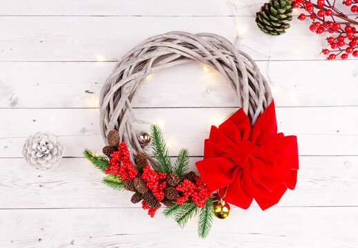 round new year ring with red ribbon and conifer wrapped in lights
