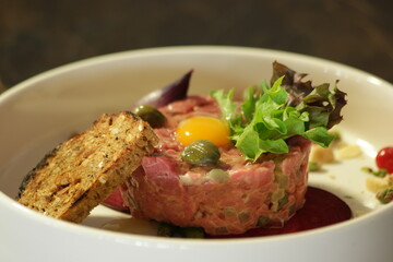 Salmon tartare with lettuce salad and egg. Tasty dish at restaurant close up. Gourmet food concept.