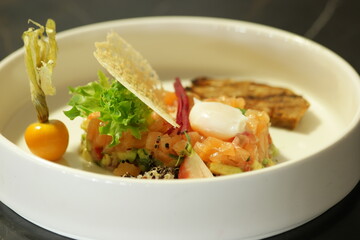 Salmon tartare in white bowl. Luxury appetizer restaurant food.