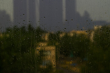 Raindrops on the window. View of the sky, trees and buildings through drops of rain covered window. The end of the rain.