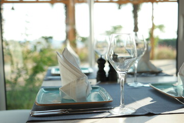 Table setting with empty wine glass, plate and napkin. Table setting for holiday. Abstract blurred background.