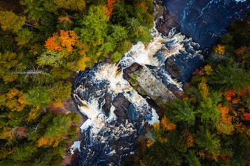 Beautiful look down travel photograph of the upper Potato River Falls waterfall cascades and whitewater rapids cutting through the deciduous and evergreen forest wilderness in Wisconsin.