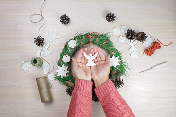 Woman making Christmas wreath and decorating it salt dough stars and angels