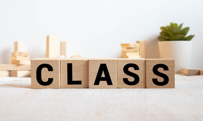 Letter block in word CLASS on wood background.