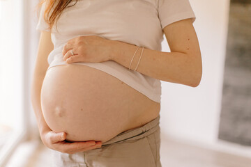 schwangere Frau streichelt sich mit den Händen sanft über ihren nackten Babybauch