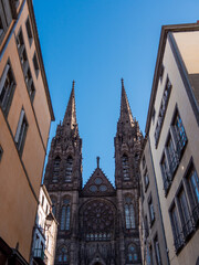 View on a street in Clermont-Ferrand. Gothic cathedral and French national monument located in the town of Clermont-Ferrand in the Auvergne, France. Blue sky and sunny day.
