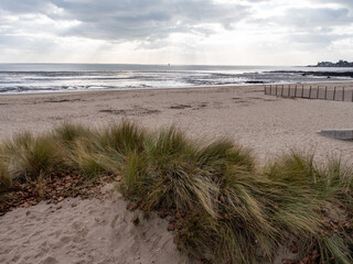 View on a beach in Saint-Nazaire, in the west of France. Cloudy sky that lets rays of light pass through. Plants in the foreground.