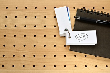 A notebook and a vocabulary book are placed on the perforated board. The word USP is written on it.