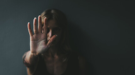 Stop violence against women! Woman raised her hand for dissuade standing against dark wall.	
 - obrazy, fototapety, plakaty