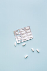 Creative medical layout made with white medicine pills, tablets, capsules, vitamins on light blue background. Minimal modern pharmacy or health care concept. Flat lay, top view, copy space