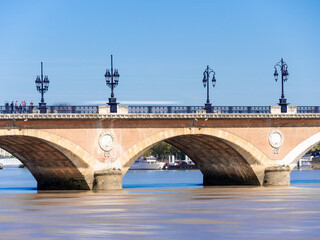 The Pont de Pierre (stone bridge) is located in the city of Bordeaux, in the southwest of France. It is one of the most famous bridges in the city. Blue sky, sunny day. Long exposure shot.