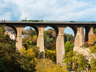 Fototapeta na wymiar The city of Luxembourg in Luxembourg. View on a bridge in the greenery. Autumn. Some clouds. 