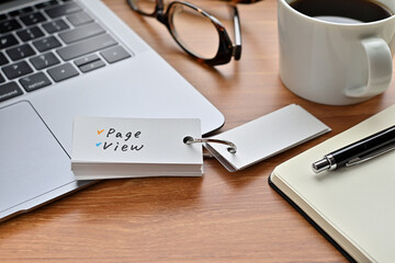 There's a laptop computer, a notebook, a pen and an open vocabulary book on the desk. The word Page View is written on it.