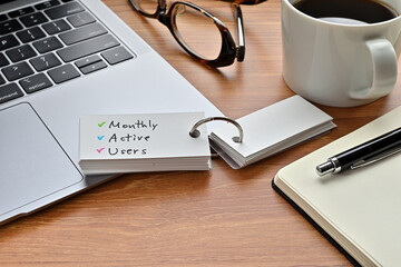 There is a piece of paper with a graph printed on it, a clipboard, and an open vocabulary book on the desk. There is the word Monthly Active Users on it.