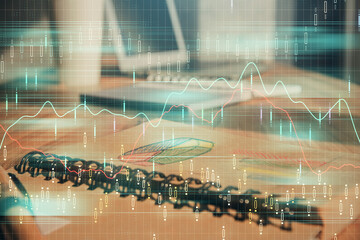 Double exposure of financial graph drawings and desk with open notebook background. Concept of forex market