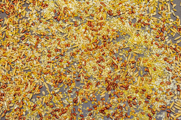 Mix of variety of cereals scattered on black stone background.