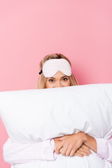  woman in blindfold covering face with pillow on pink background