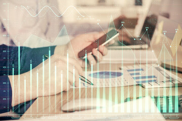 Double exposure of man's hands holding and using a digital device and forex graph drawing. Financial market concept.