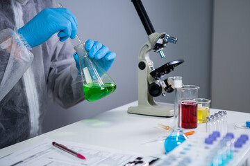 Scientist shakes green biochemical product in erlenmeyer flask mixing and research in laboratory....
