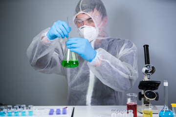 Scientist shakes green biochemical product in erlenmeyer flask mixing and research in laboratory....