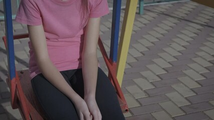 Quarantined sad child. A stressed quarantined child sits on the swing in the yard.