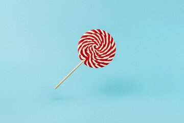 Colorful lolipop on blue background, wooden stick, red and white spiral, childhood sweets, Christmas concept