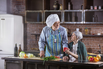 Senior couple cooking together. Man is wearing chef hat and chopping fresh vegetables.