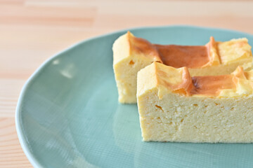 Two slices of cheesecake are placed on a green plate.