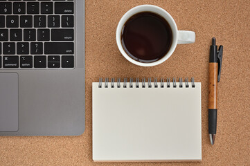 There's a laptop, a pen, a notepad, and coffee. Taken from top view.