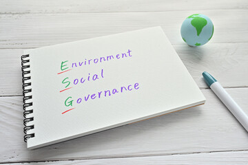 A sketchbook with environmental, social and governing words is placed on a white board along with a ball of earth.