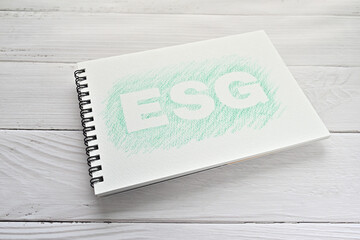 There is a sketchbook with an illustration of the ESG on white wood board.