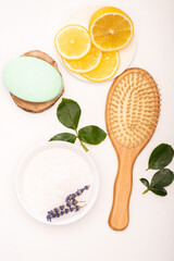 Fototapeta na wymiar top view of brush, bowl with lavender, sliced lemon, soap, and rose leaves on white, stock image