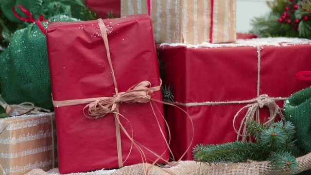 Packed boxes with gifts tied with twine and sprinkled with snow. Green and red colors as a traditional symbol of the New Year and Christmas holidays. Slow camera movement from left to right.