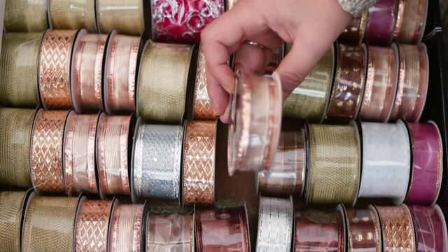 Spools of various pastel fabric ribbons in the store, wide range of haberdashery goods. The buyer selects the desired product for gift wrapping on the eve of the holidays. 
