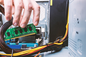 male person or technician worker installing ddr ram memory module to a desktop pc case. close up....