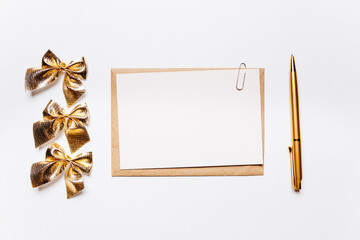 Blank note with envelope, bow and gold pen on white background