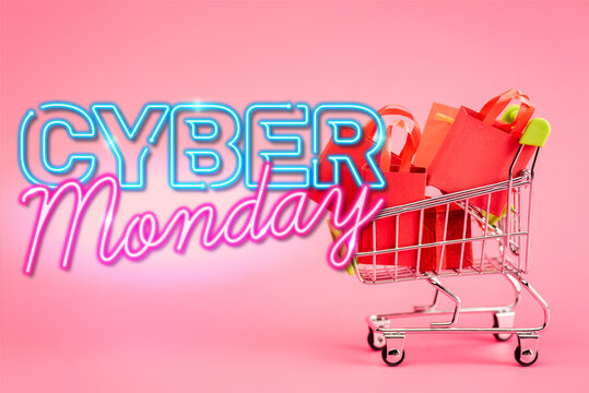 red paper bags in small shopping trolley near cyber monday lettering on pink, stock image