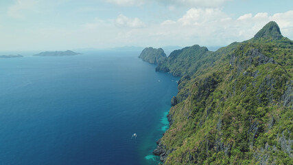 Fototapeta na wymiar Aerial view of mountain island with green tropic forest. Epic landscape of ocean bay greenery cliff shore at sand beach. Boats at sea gulf with turquoise seascape of Palawan Island, Philippines, Asia