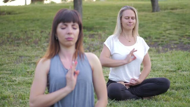 Girls meditates in lotus pose on green grass at sunset. Healthy lifestyle and relaxation
