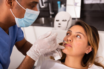 Attractive Latina receiving injections for face skin tightening at aesthetic cosmetology clinic