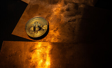 A bitcoin coin lying on a shiny copper plate.