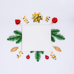 Christmas postcard with paper blank, golden decorations, fir tree branches, confetti and sparkles on light background. Flay lay, top view, copy space