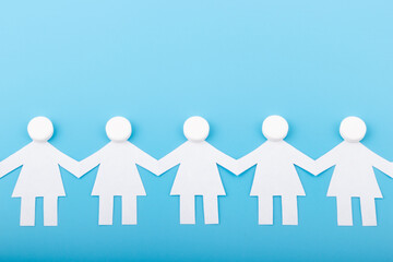 A chain of paper people with pills on a blue background. Medicine concept.