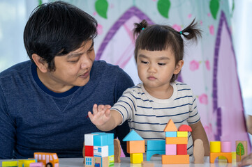 Happy Family ,Parents play Developmental toys with their little girl in home sweet home.
