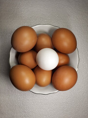 Close-up view of raw chicken eggs in bowl on white cloth background