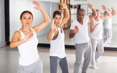 Fototapeta premium Young men and women mastering martial arts techniques for self-defense at practice in training room ..