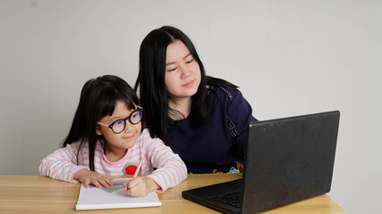 Covid-19 Coronavirus and Learning from home, Home school kid concept.Little asian girl study with online learning and asian mother work from home with laptop.Education and Social distancing concept.